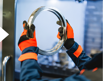 Gloved hands inspecting circular metal object
