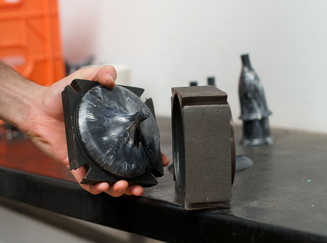 Person examining casting mold on table